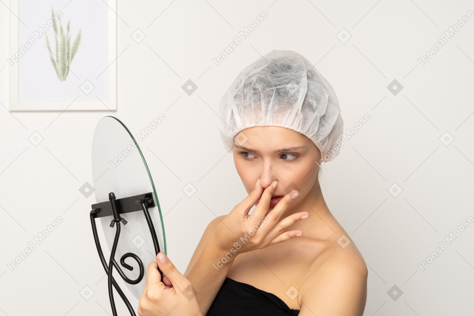 Unhappy woman in surgical cap looking in the mirror and touching her nose