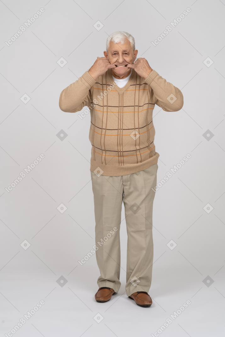 Vista frontal de un anciano con ropa informal poniendo los dedos en la boca