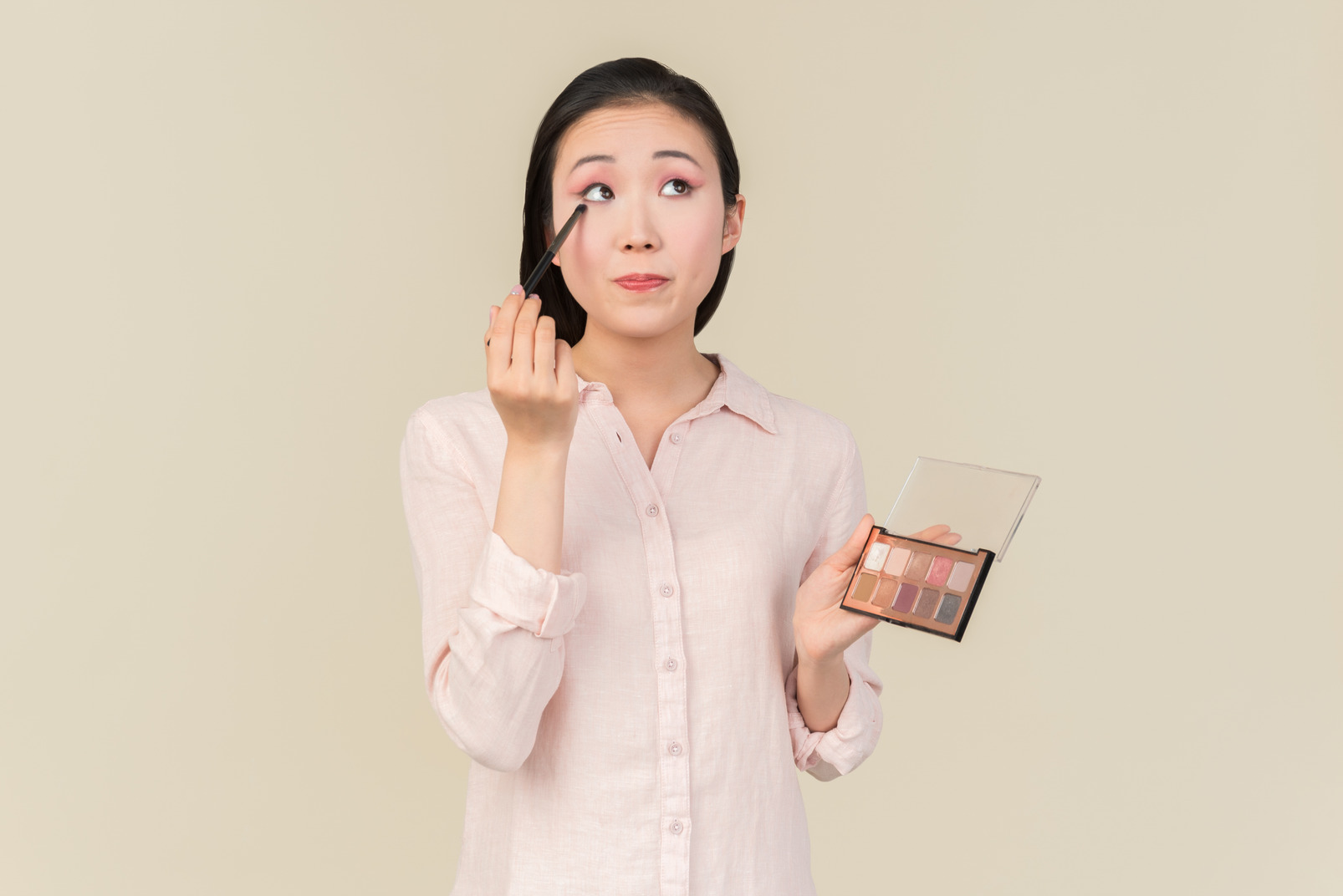 Young asian woman focused on eyeshadow application