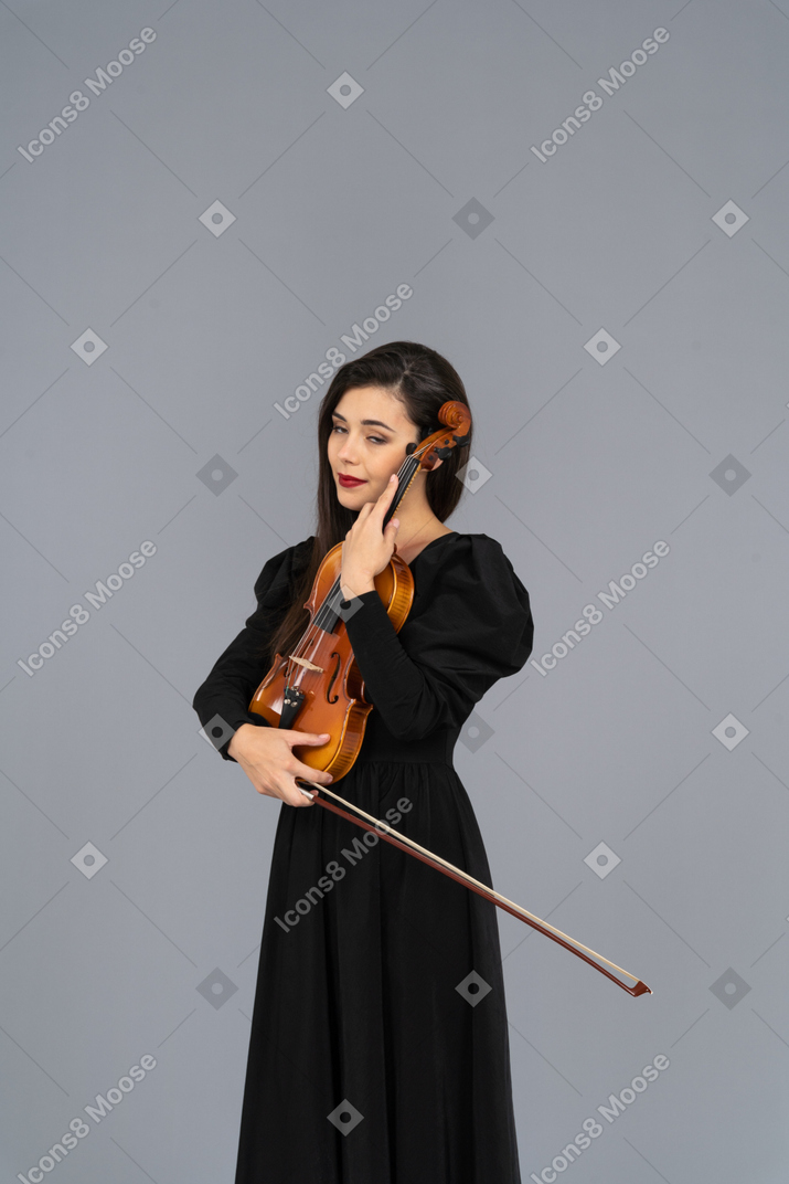 Gros plan d'une jeune femme en robe noire embrassant son violon