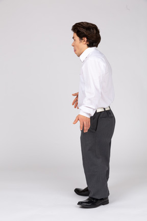 Vista laterale di un giovane uomo in abiti casual da lavoro che mostra la sua lingua