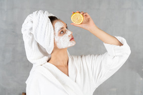 Close-up de uma mulher de roupão de banho com um limão na mão