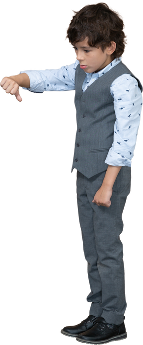 Vista lateral de un niño con traje gris que muestra el pulgar hacia abajo