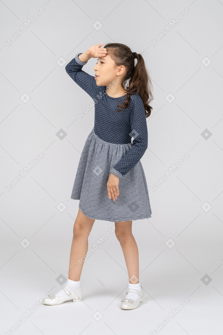 Vista de tres cuartos de una niña dando un paso con una mano en la frente