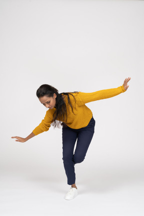 Front view of a girl in casual clothes posing on one leg with outstretched arms