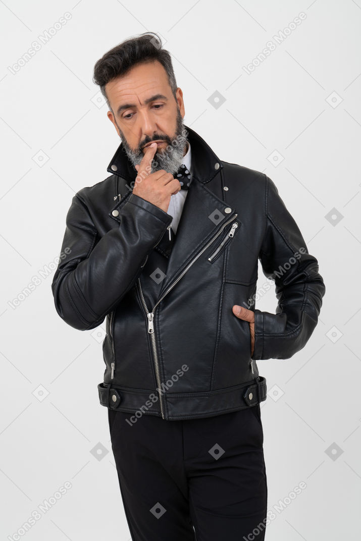 Pensive mature man holding his one hand in jacket and touching chin with a finger