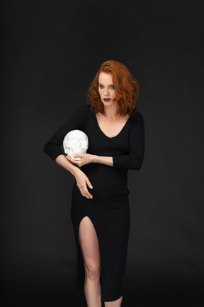 A frontal view of a beautiful young woman posing with a skull