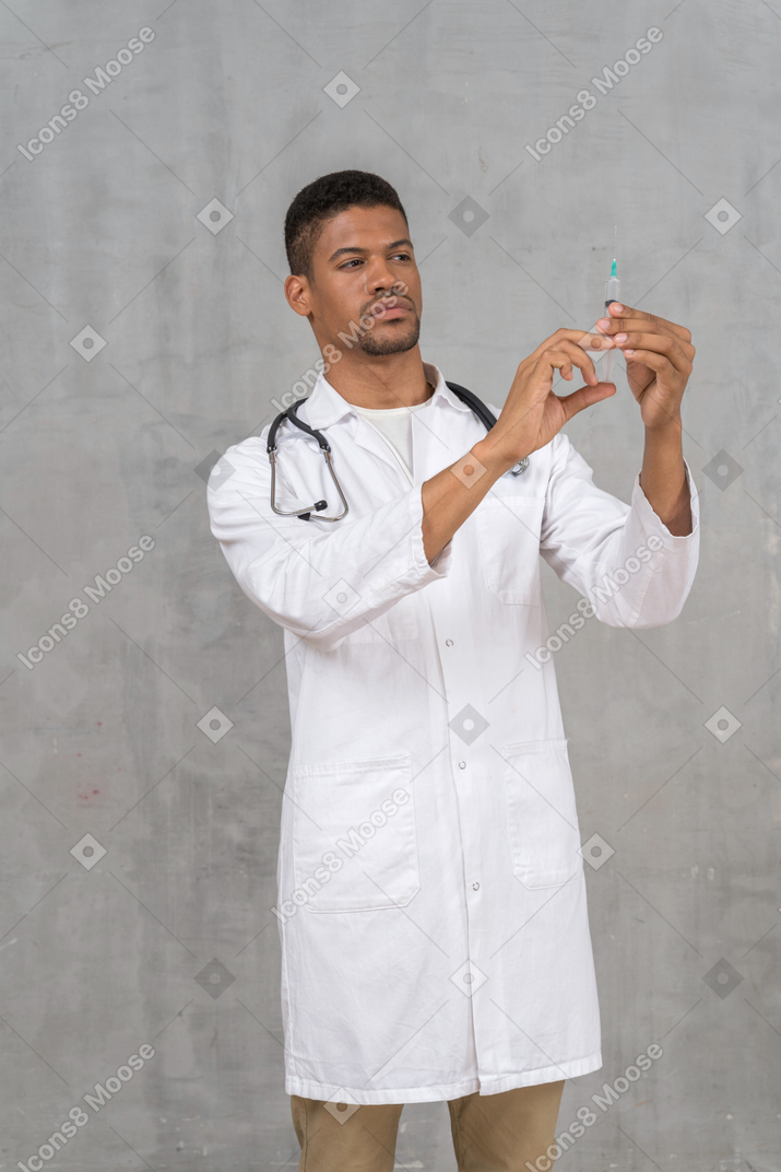 Doctor de sexo masculino que prepara una jeringuilla