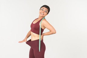 Young indian pulling off sports leggins with cloth ruler on her neck