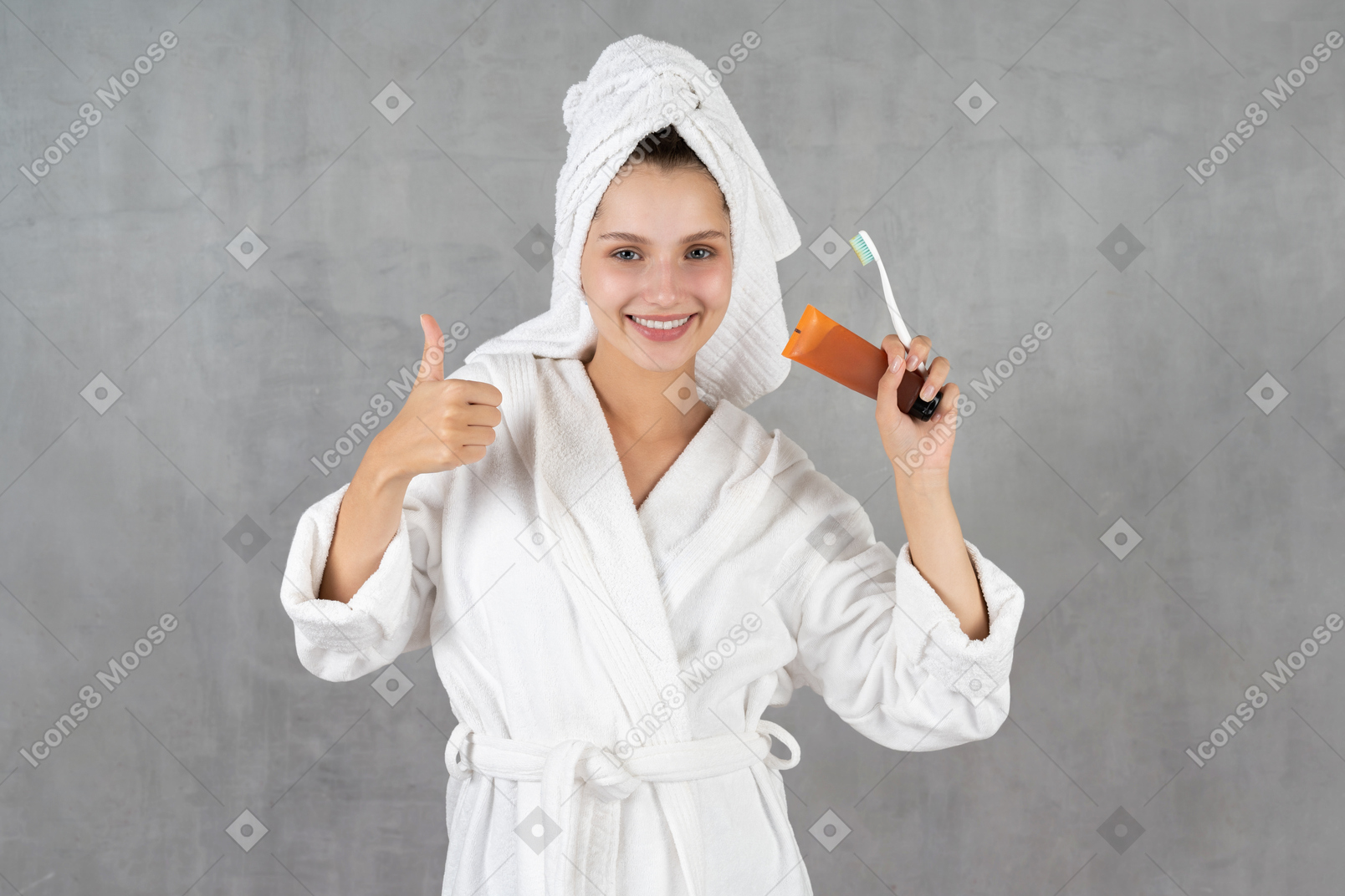 엄지손가락을 보여주는 목욕 가운에 웃는 여자