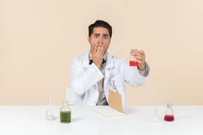 Worried young male caucasian scientist looking at bulb