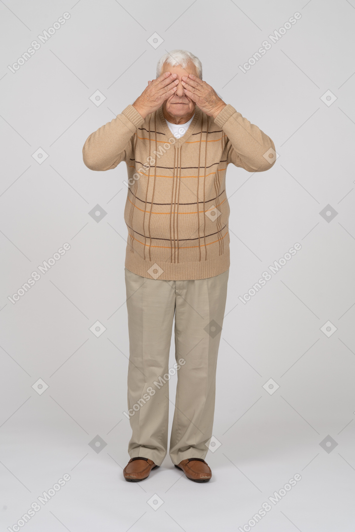 Vista frontale di un vecchio in abiti casual che copre gli occhi con le mani