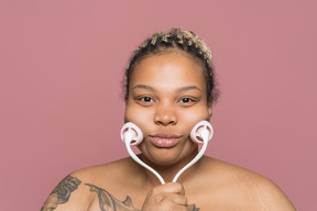 Shirtless african-american woman applying a face massage roller