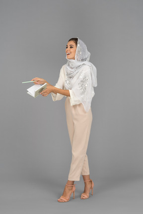 Excited middle eastern woman with a notebook looking aside