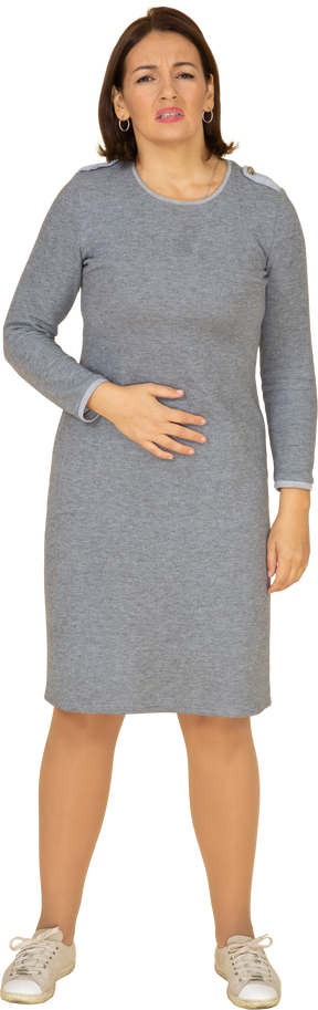 Front view of a woman in grey dress suffering from stomachache