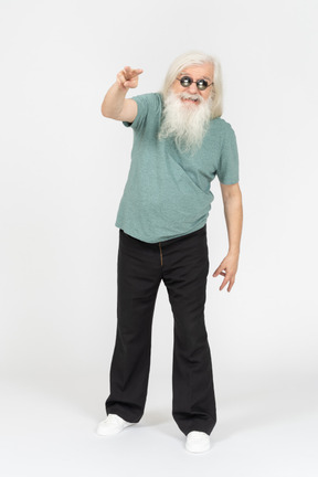 Front view of old man in sunglasses pointing two fingers at camera