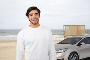 A man standing next to a car on a beach