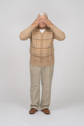 Vista frontal de um velho em roupas casuais, cobrindo os olhos com as mãos