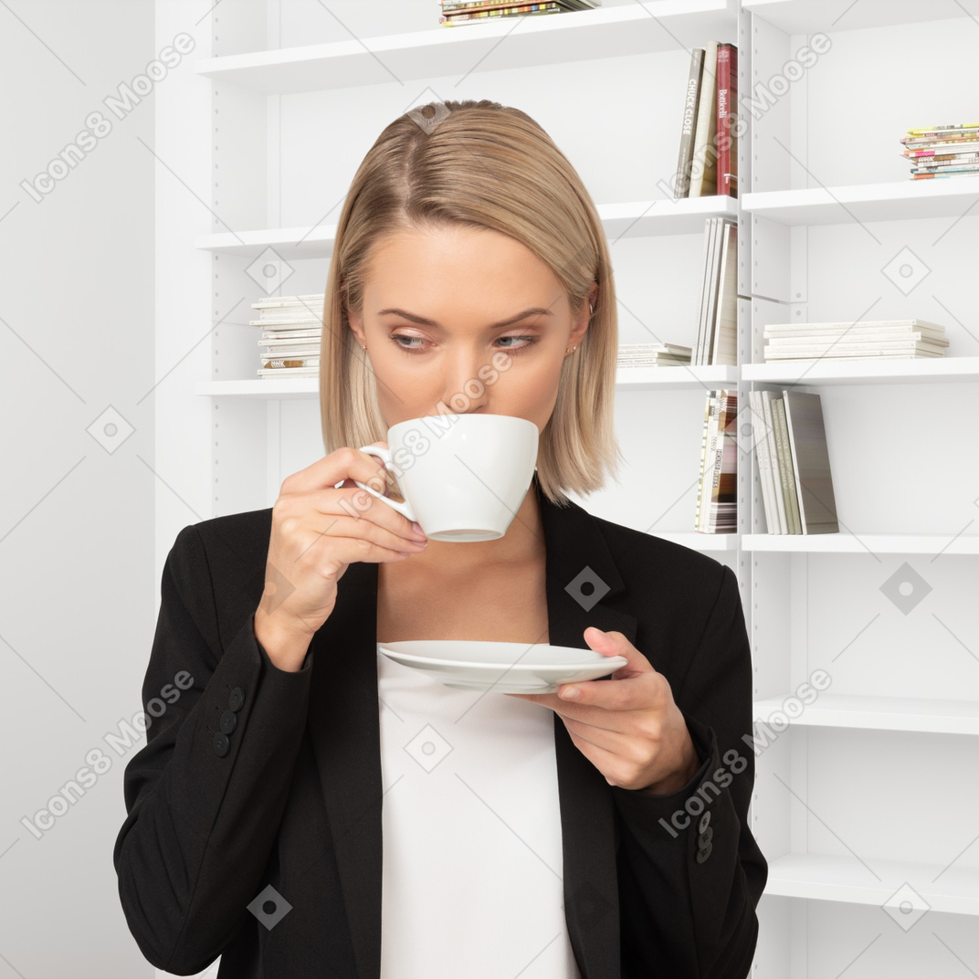 A woman holding a plate and drinking a cup of coffee
