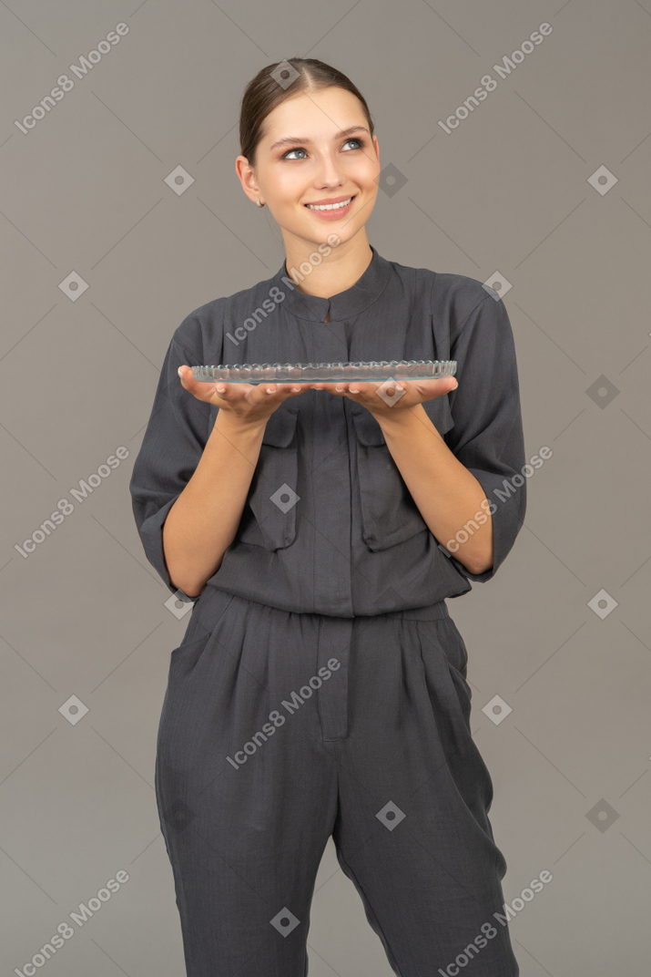 Vista frontale di una giovane donna in tuta che tiene in mano una lastra di vetro