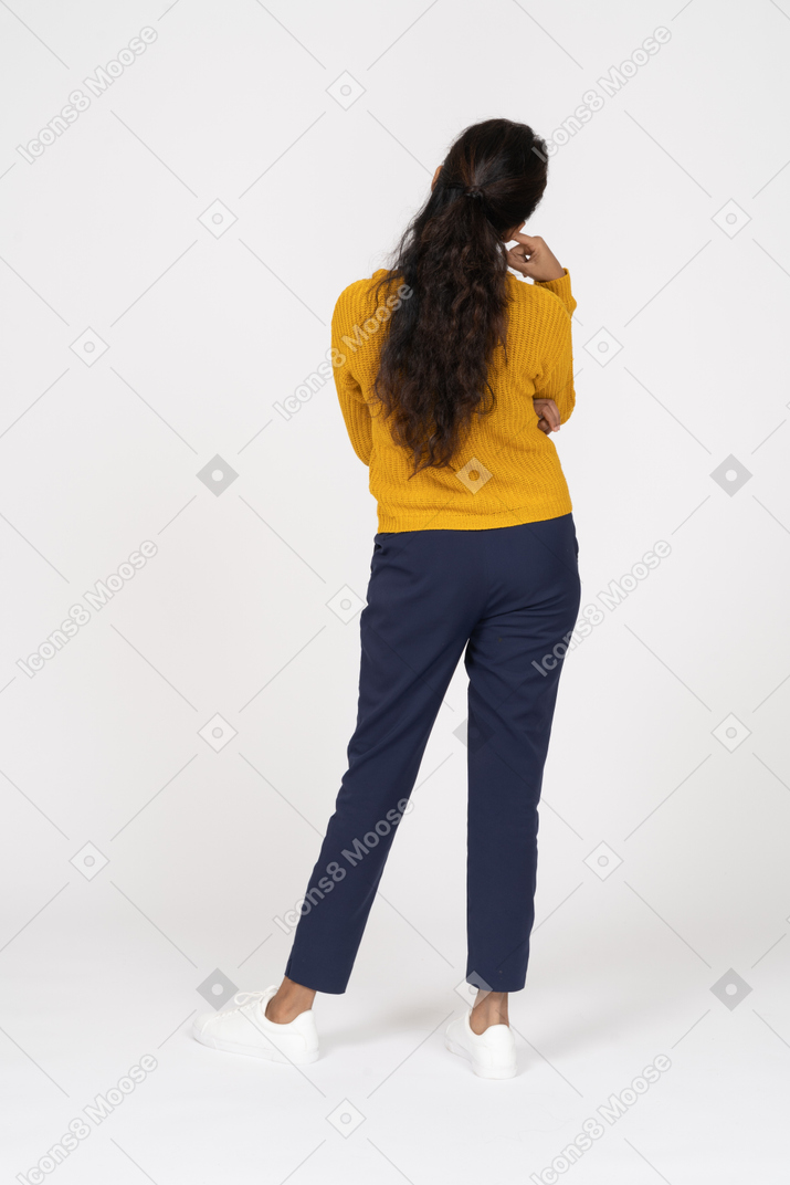 Rear view of a thoughtful girl in casual clothes touching chin with finger