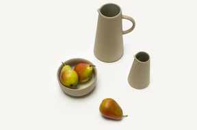 Bowl with pears and some grey jars on a white background