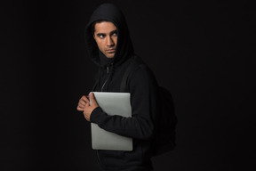 Hacker guy standing in the dark and holding laptop