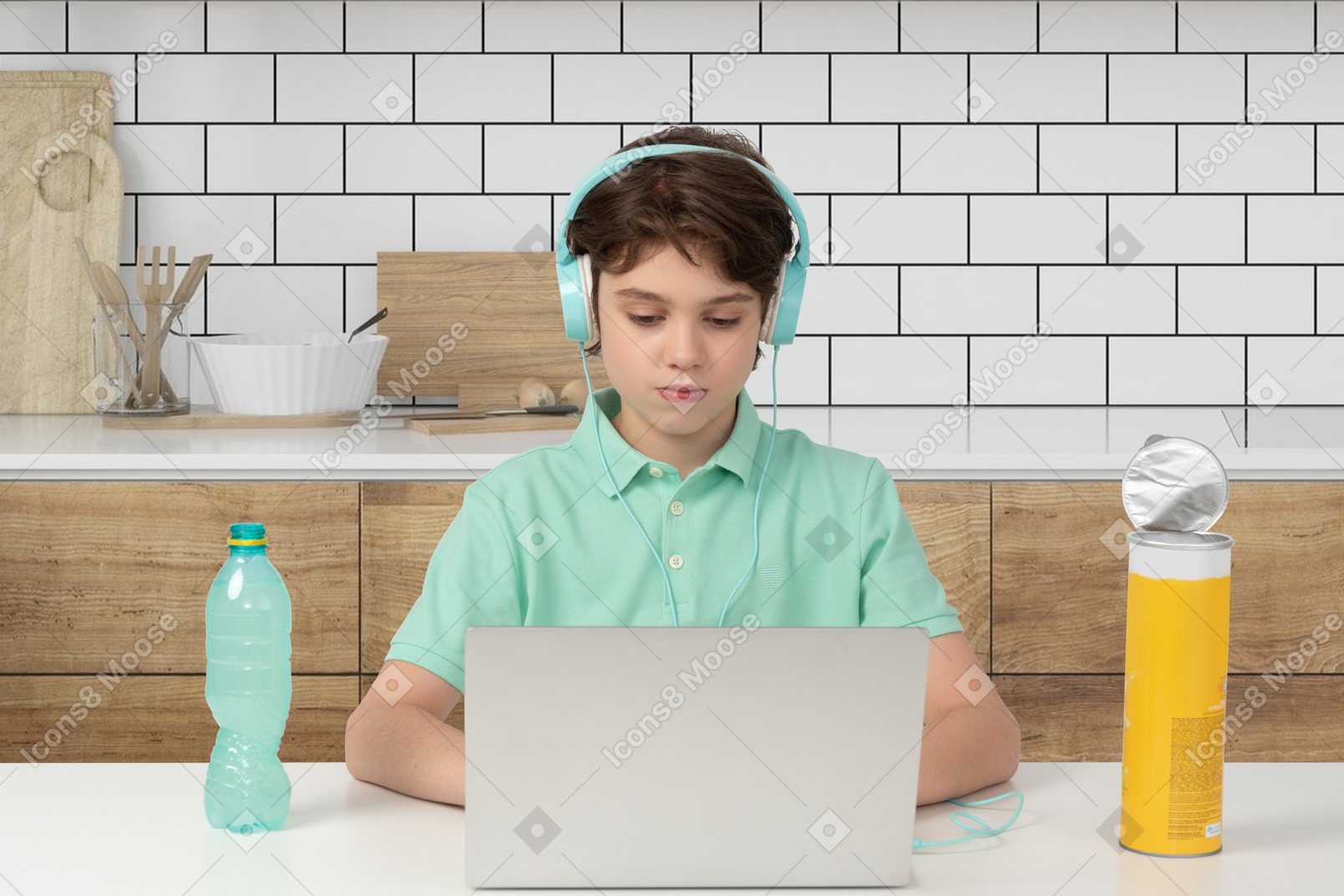 A boy wearing headphones sitting at a table using a laptop