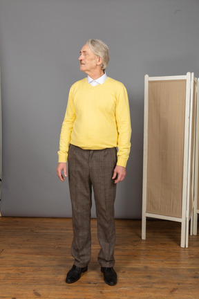 Vista frontal de um homem idoso com um pulôver amarelo virando a cabeça