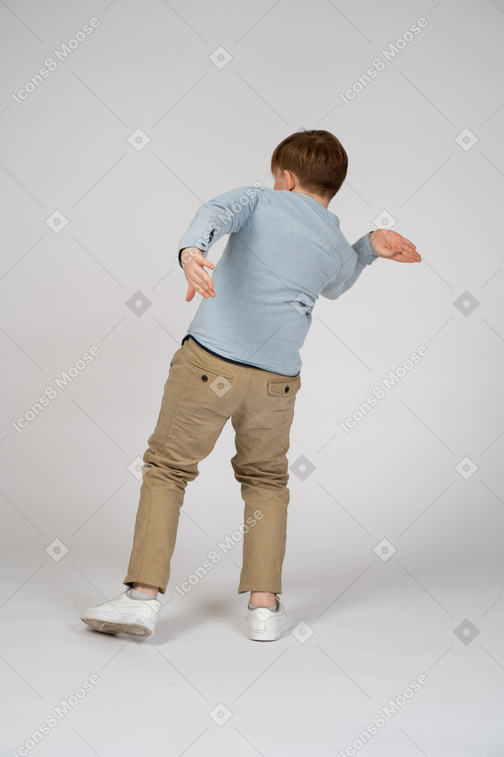 Back view of a young boy doing a weird pose