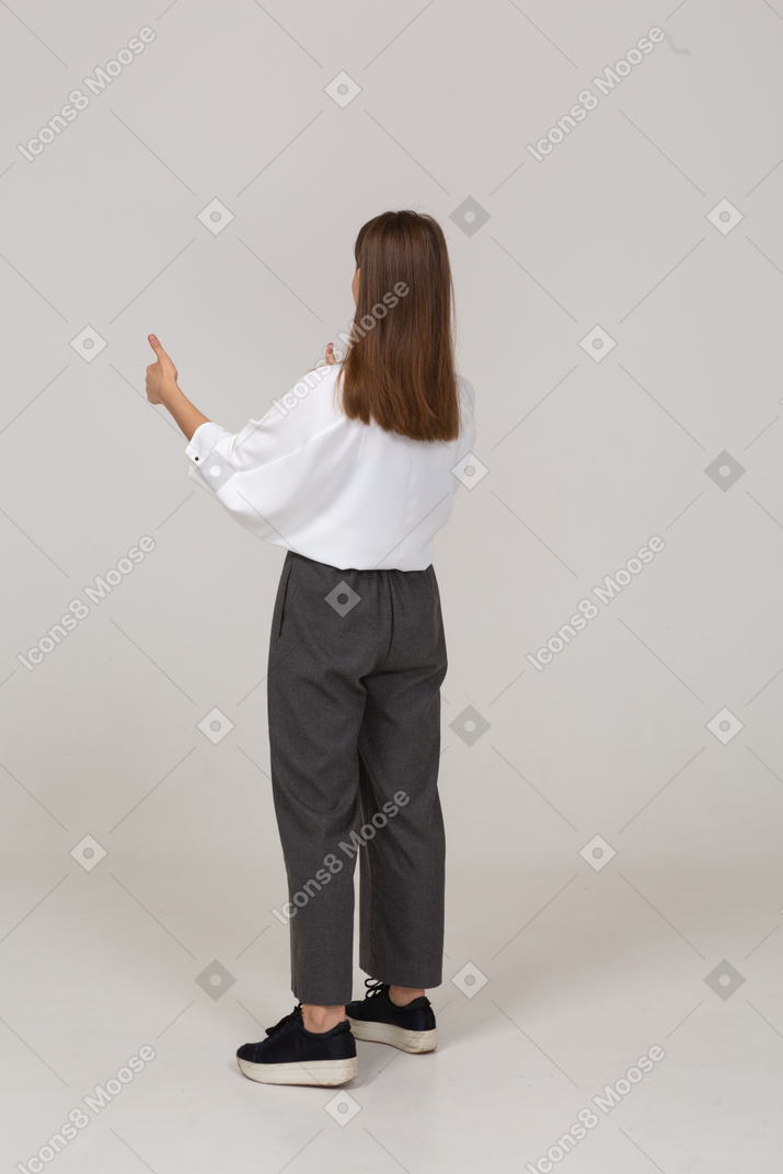 一位身着办公服的年轻女士竖起大拇指的四分之三后视图