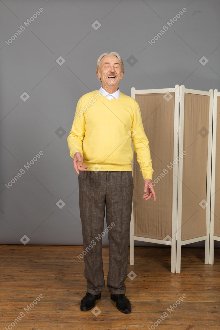 Vue de face d'un vieil homme souriant gesticulant les yeux fermés
