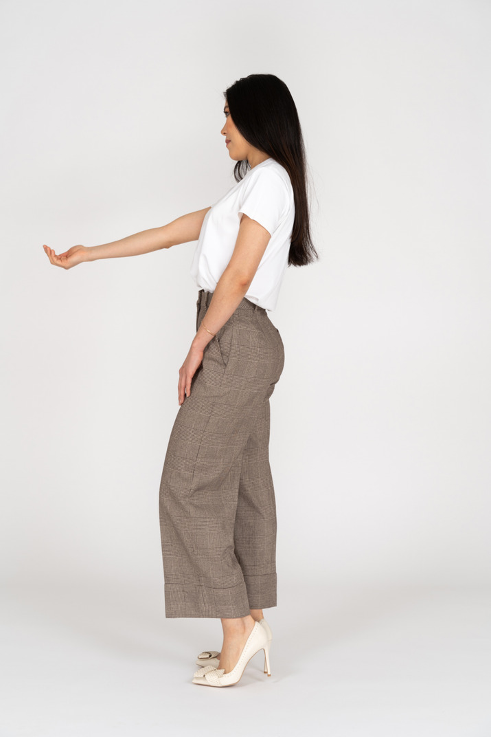 Side view of a young lady in breeches and t-shirt outstretching her hand