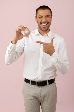 Atractivo joven sosteniendo una moneda de etéreo.