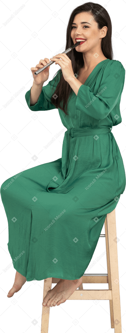 全长的微笑的年轻女士，穿着绿色的衣服，坐在椅子上，一边演奏单簧管
