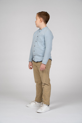 一个穿着休闲服的男孩站着不动，看着一旁的侧视图