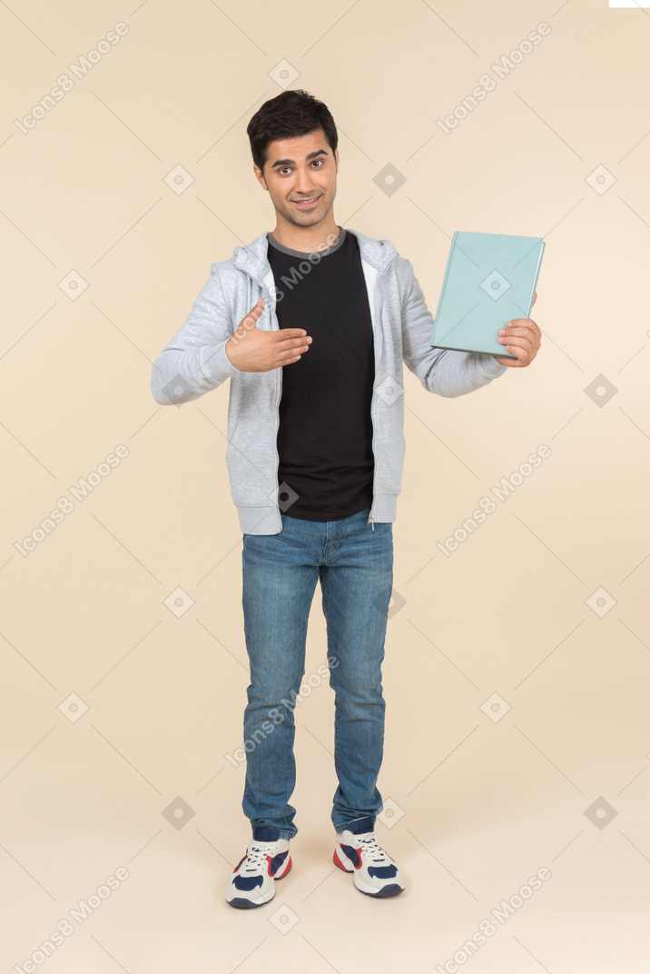 Young caucasian man pointing at book he's holding
