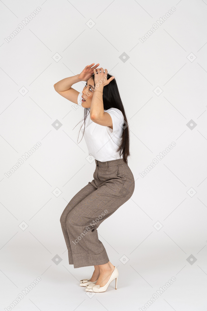 Three-quarter view of a scared young woman in breeches touching her head