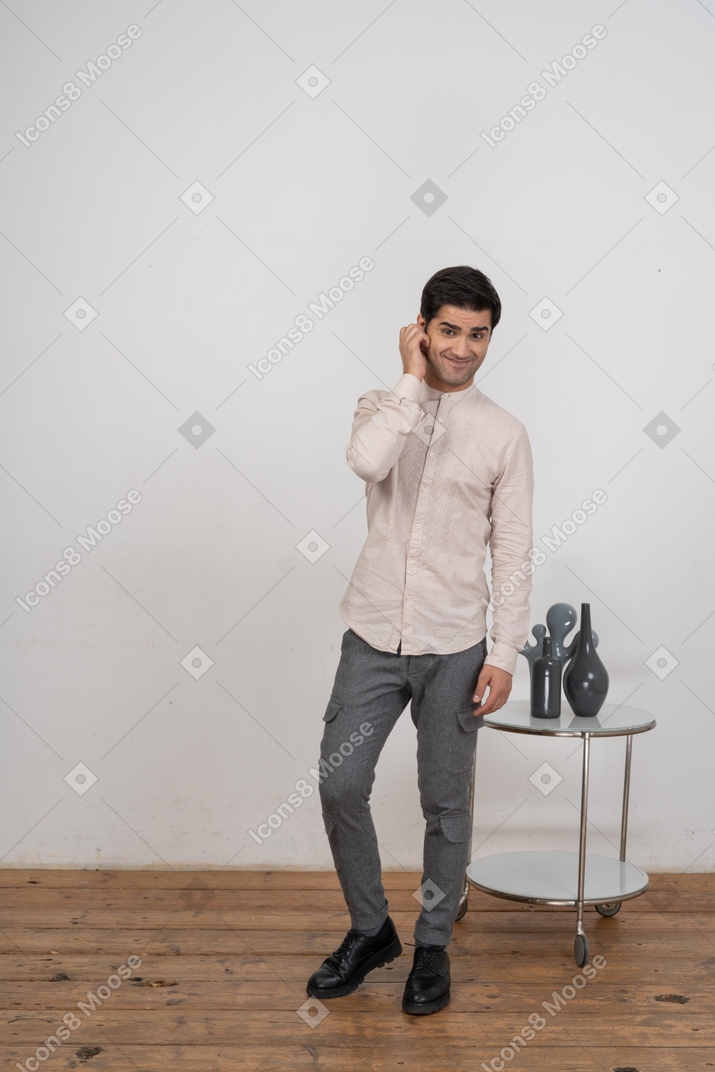 Vista frontal de um homem com roupas casuais tocando a orelha