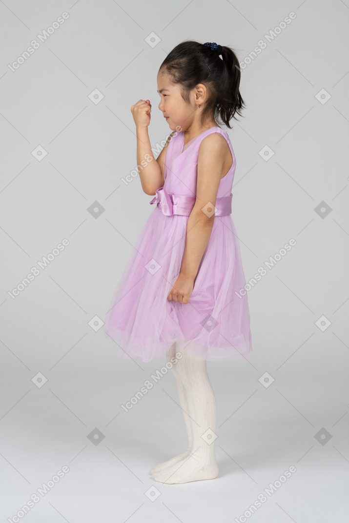 Вид сбоку на маленькую девочку, показывающую кулак