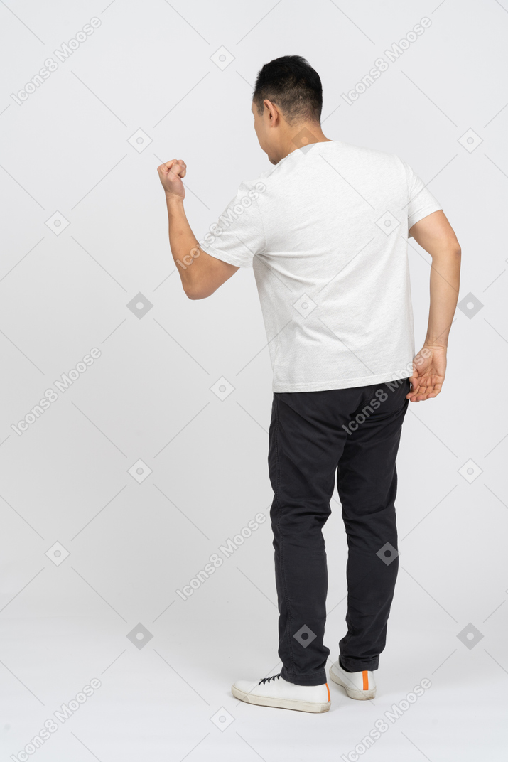 Rear view of a man in casual clothes threatening someone with fist