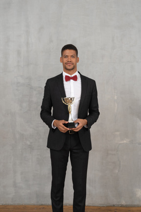 Hombre feliz con traje posando con un premio