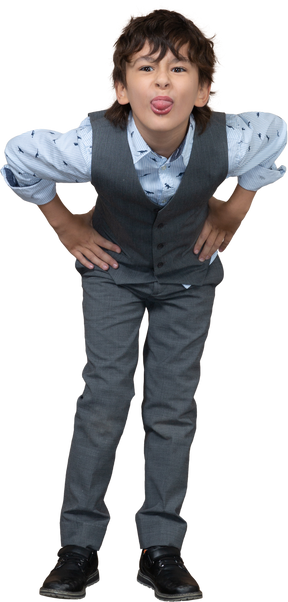Vista frontale di un ragazzo in abito grigio in posa con le mani sui fianchi e lingua showin