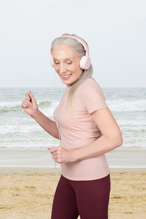A woman with headphones is running on the beach