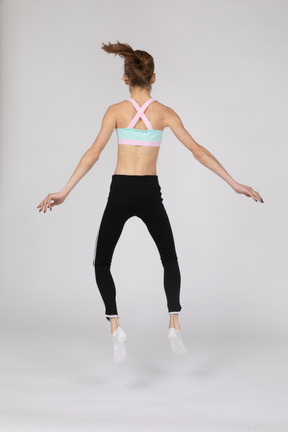 Side view of a teen girl in sportswear squatting and putting hands on hips