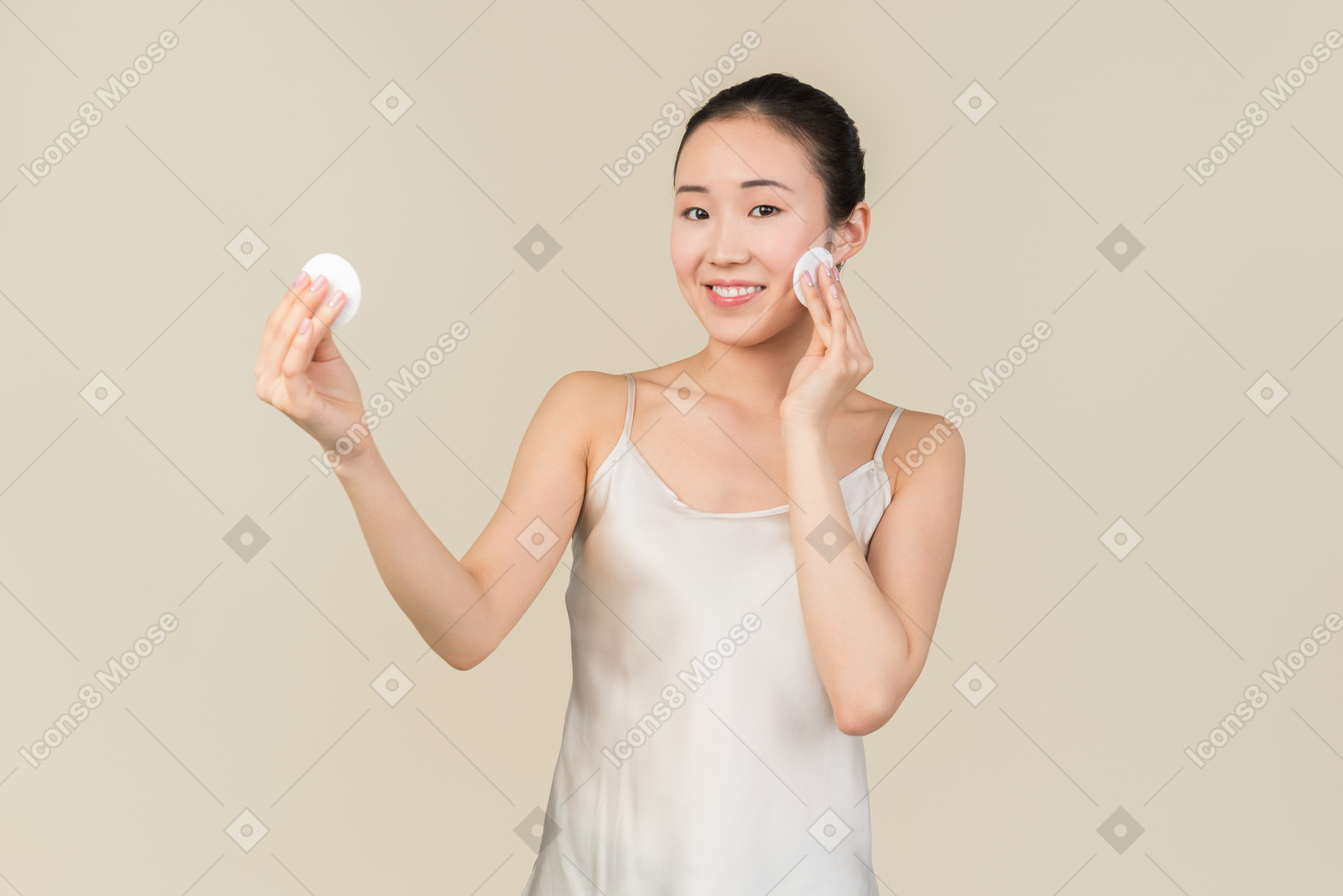 Young asian woman holding cotton pads in both hands and cleaning face skin
