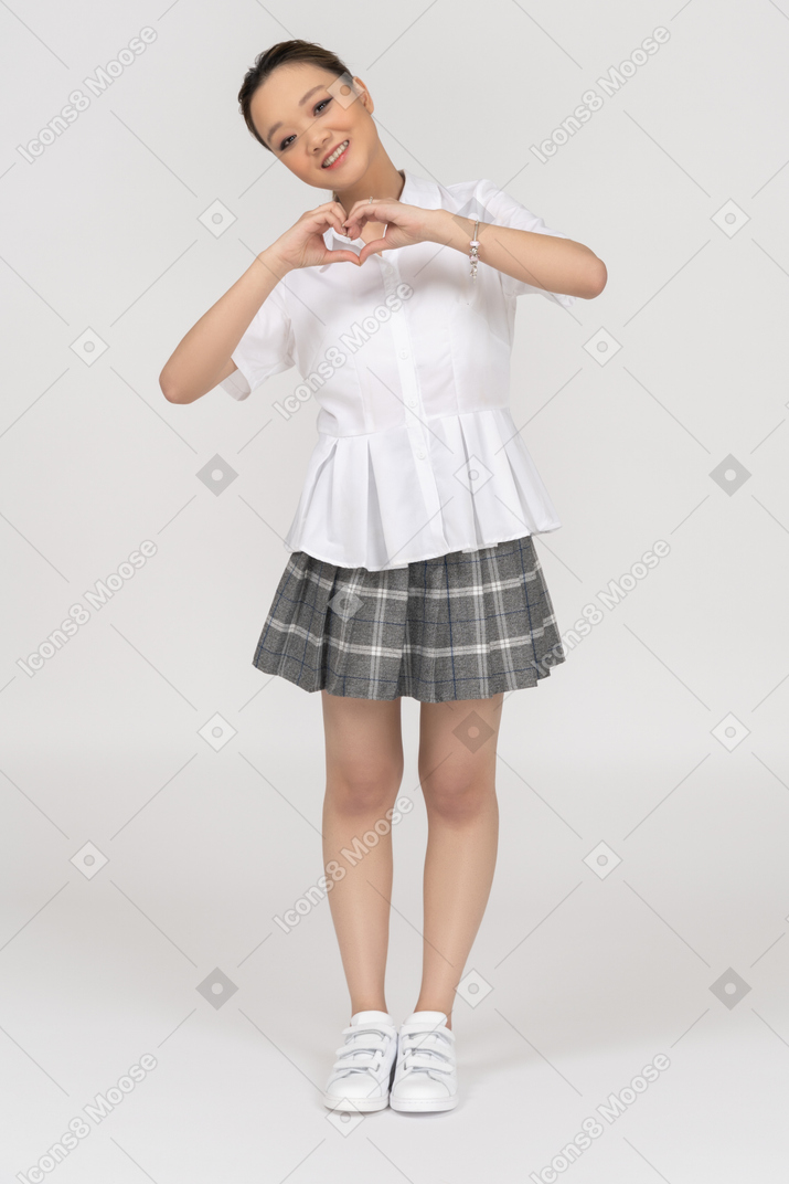 Cheerful young girl making a heart gesture