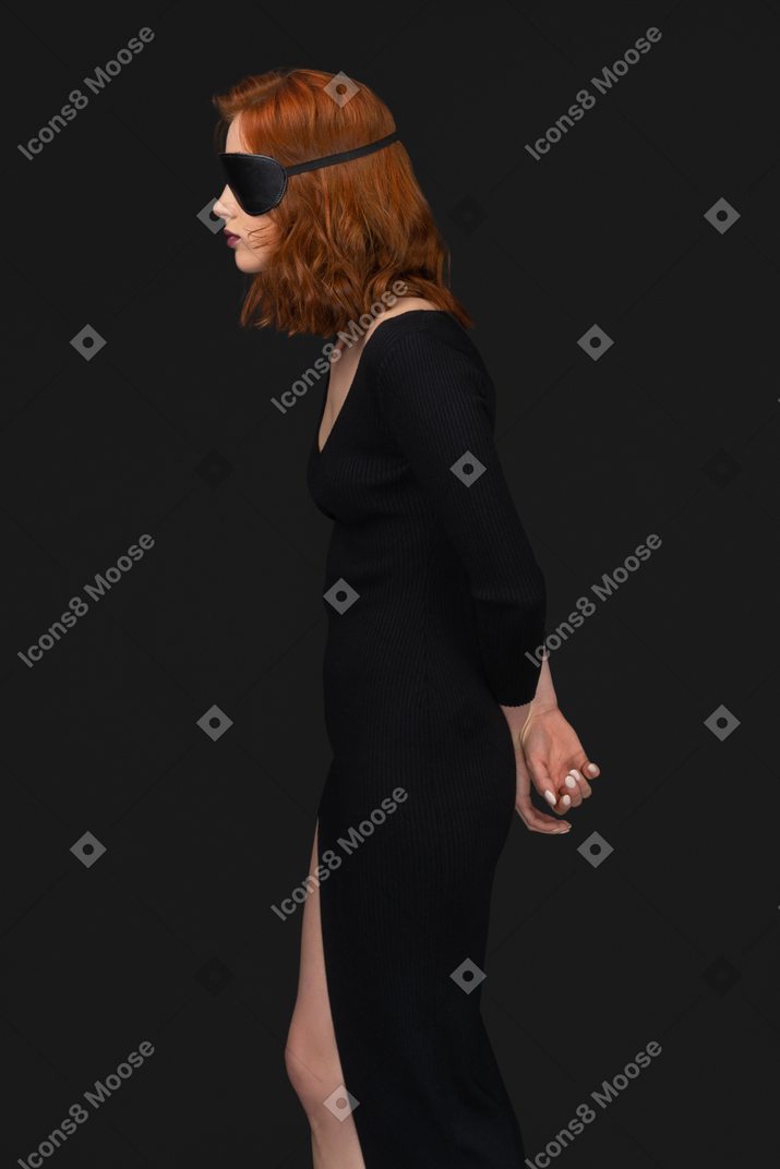 A side view of the sexy young woman dressed in black with the sleep mask on her eyes