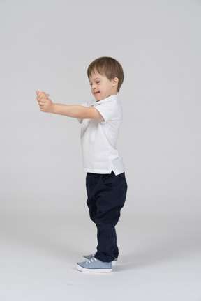 Side view of little child standing with arms extended