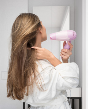 Woman drying her hair with pink hair dryer